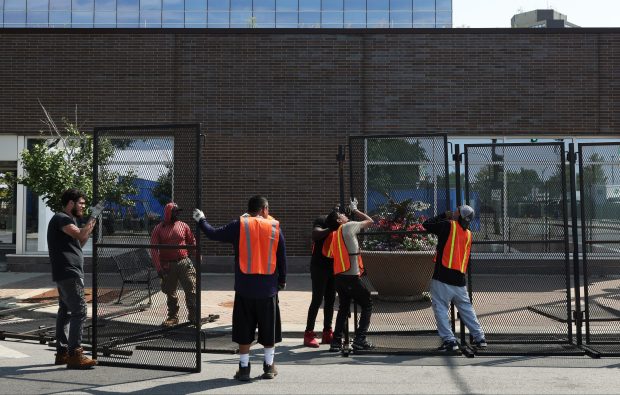 Workers install metal barricades on West Adams Street in preparation for the Democratic National Convention at the United Center on Aug. 14, 2024, in Chicago. (John J. Kim/Chicago Tribune)